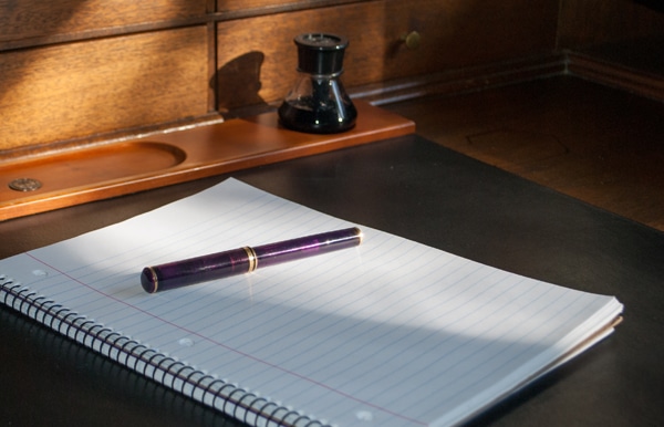 purple fountain pen on blank notebook
