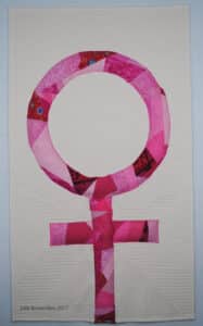 art quilt of pink crazy pieced woman symbol on white background